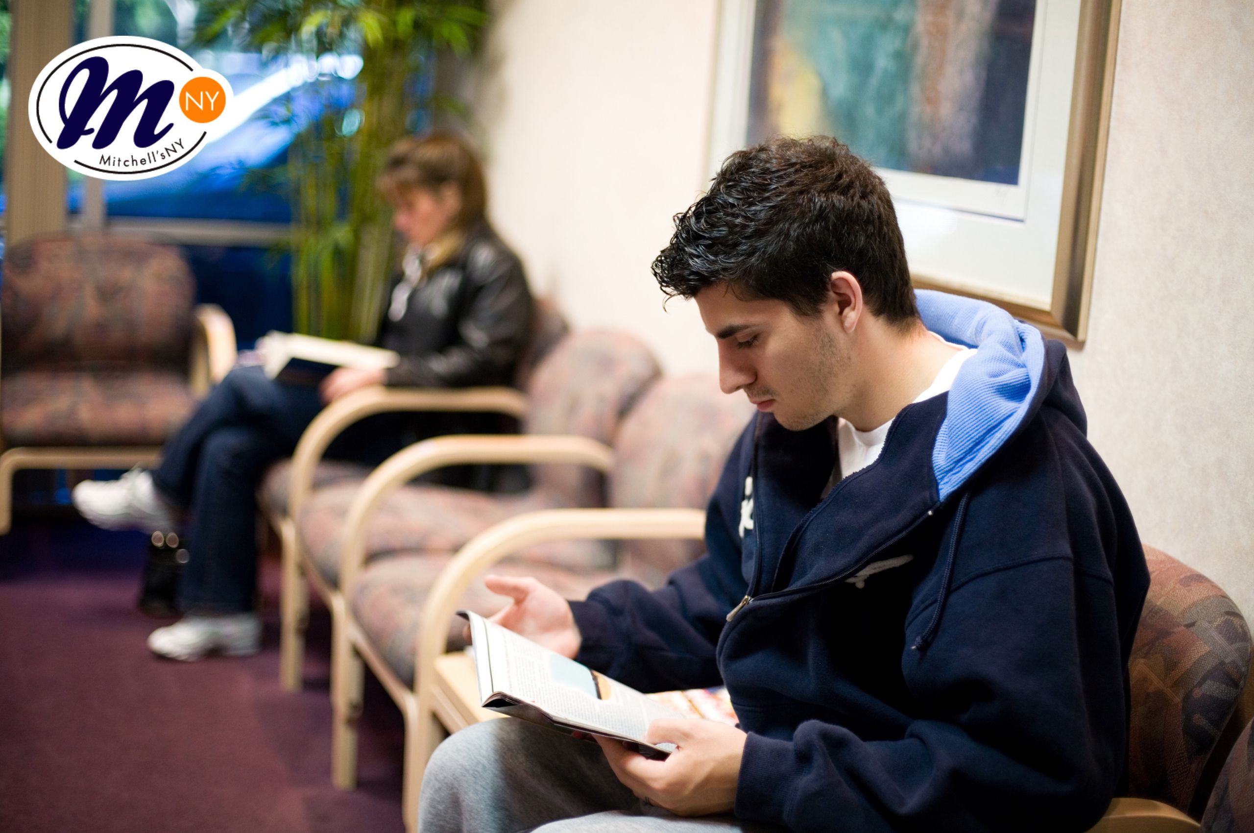 Two seated customers reading magazines in a waiting room.